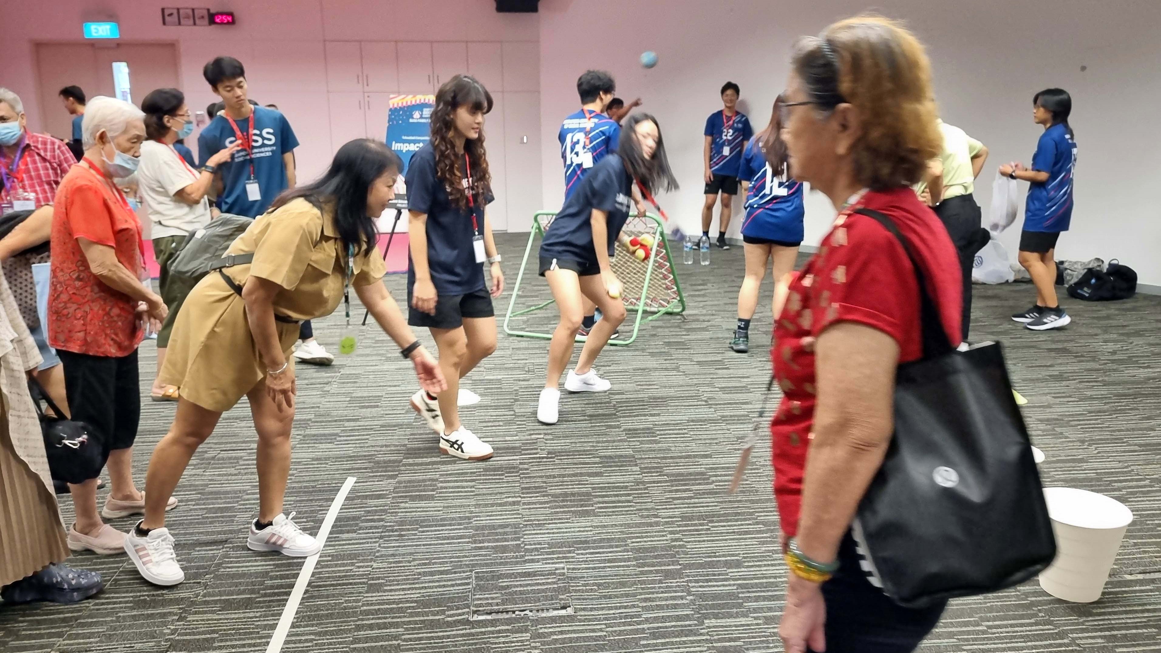 SUSS Students and elderly community members enjoying a fun and engaging indoor activity session, fostering intergenerational connection and teamwork