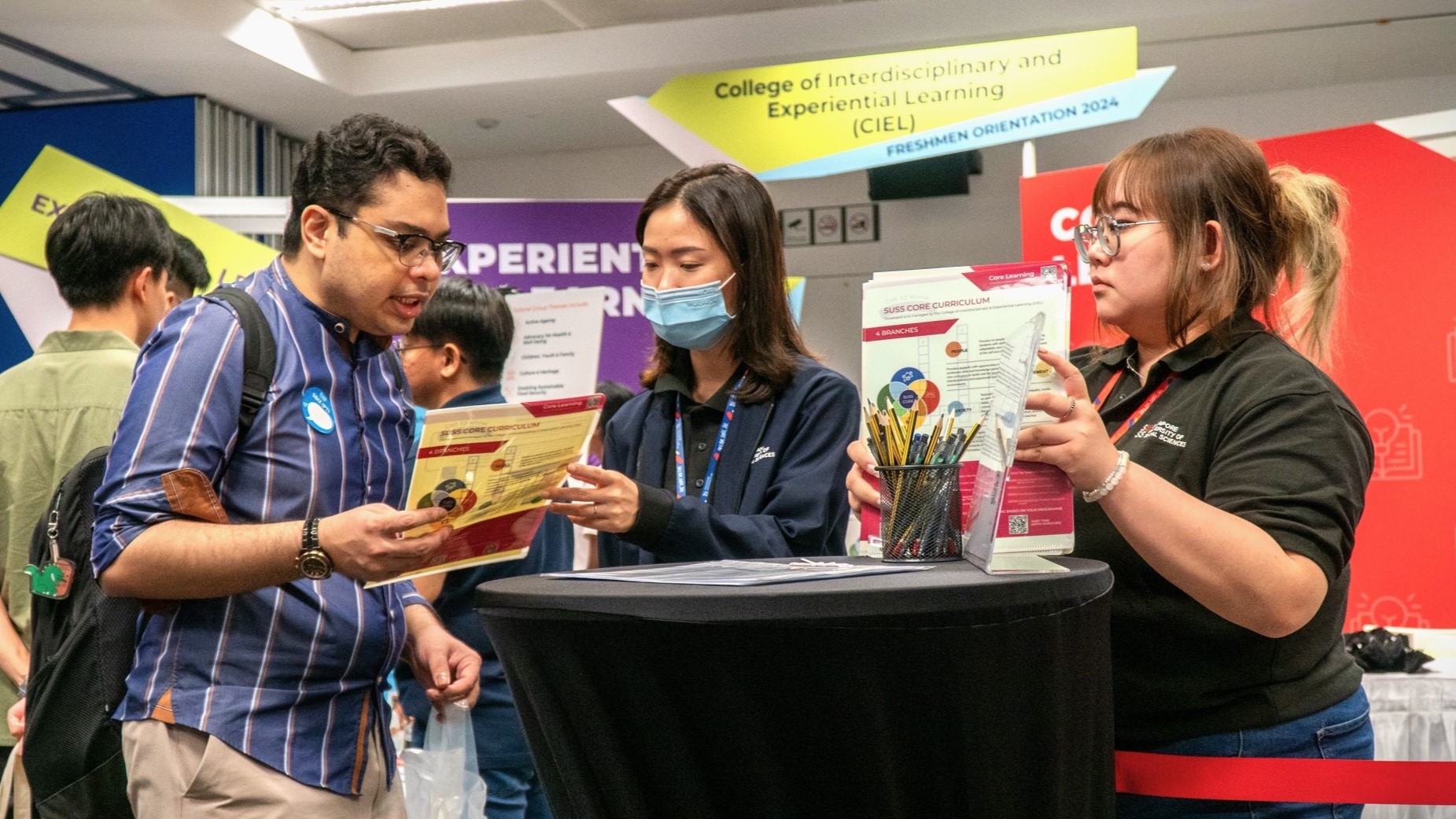 Staff from the College of Interdisciplinary and Experiential Learning booth engaging with a student